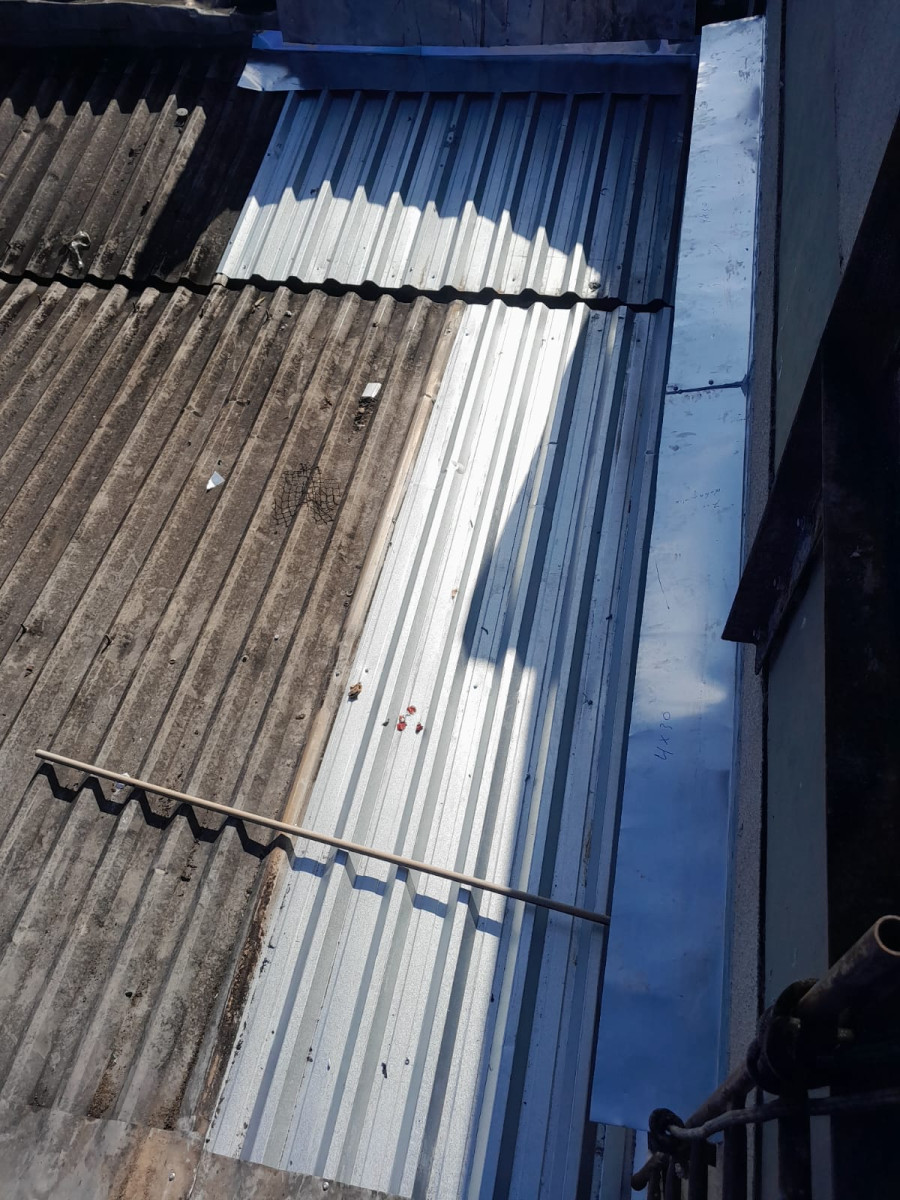 Chapa metálica nova de cobertura industrial recém-instalada, contraste com o telhado antigo