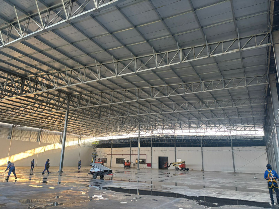 Interior de galpão industrial da Engemec com piso recém-lavado refletindo a estrutura metálica