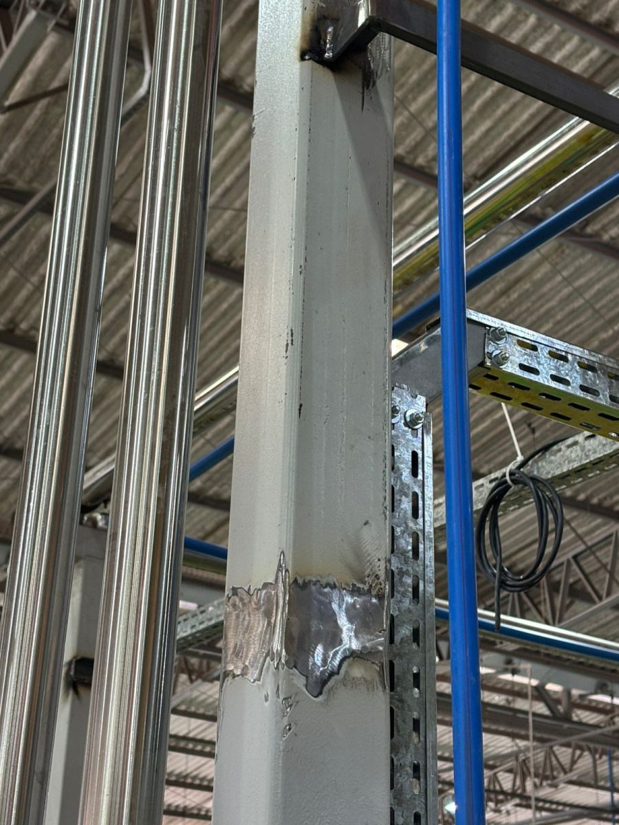 Solda em coluna estrutural durante montagem eletromecânica industrial
