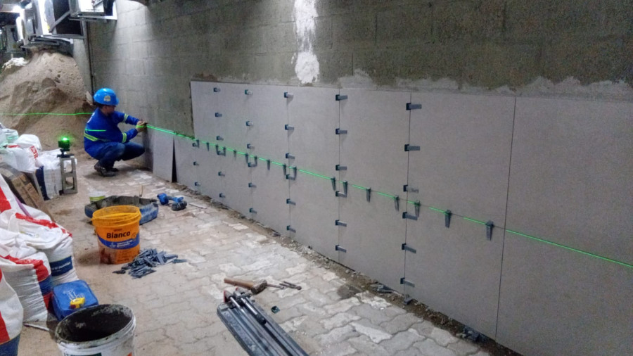 Instalação de revestimento de parede com nível a laser, obra de retrofit Engemec