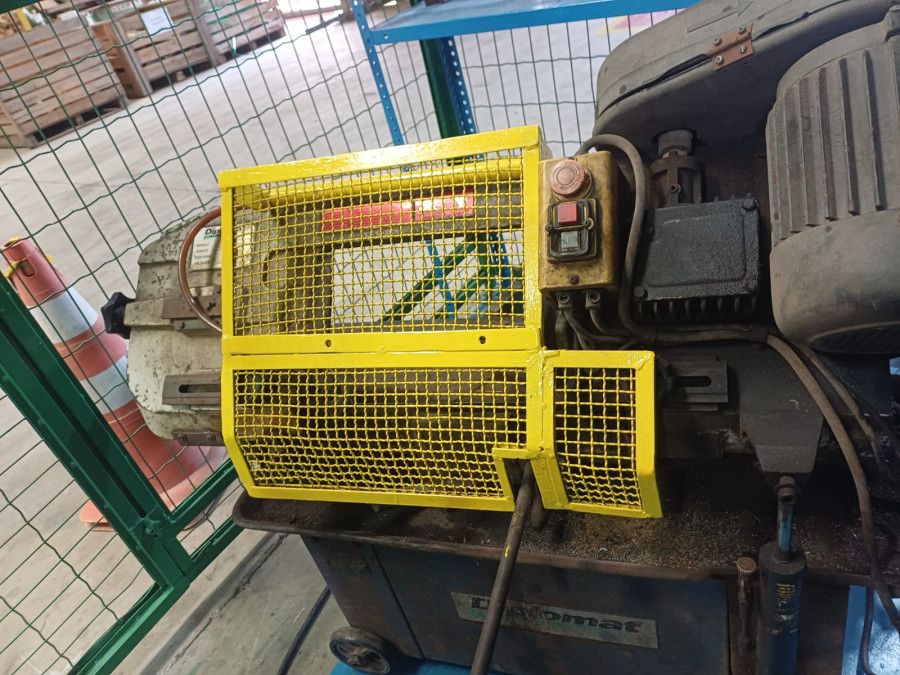 Proteção de máquina em malha metálica amarela instalada sobre motor industrial, segurança de máquinas conforme NR-12